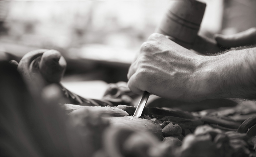 Carpenter carving traditional patterns into wood by hand.