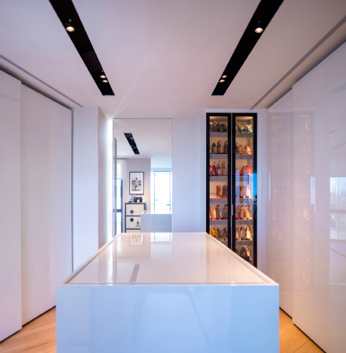 Custom-made walk-in closet with shoe racks and a chest of drawers that functions as an island with extra storage space.