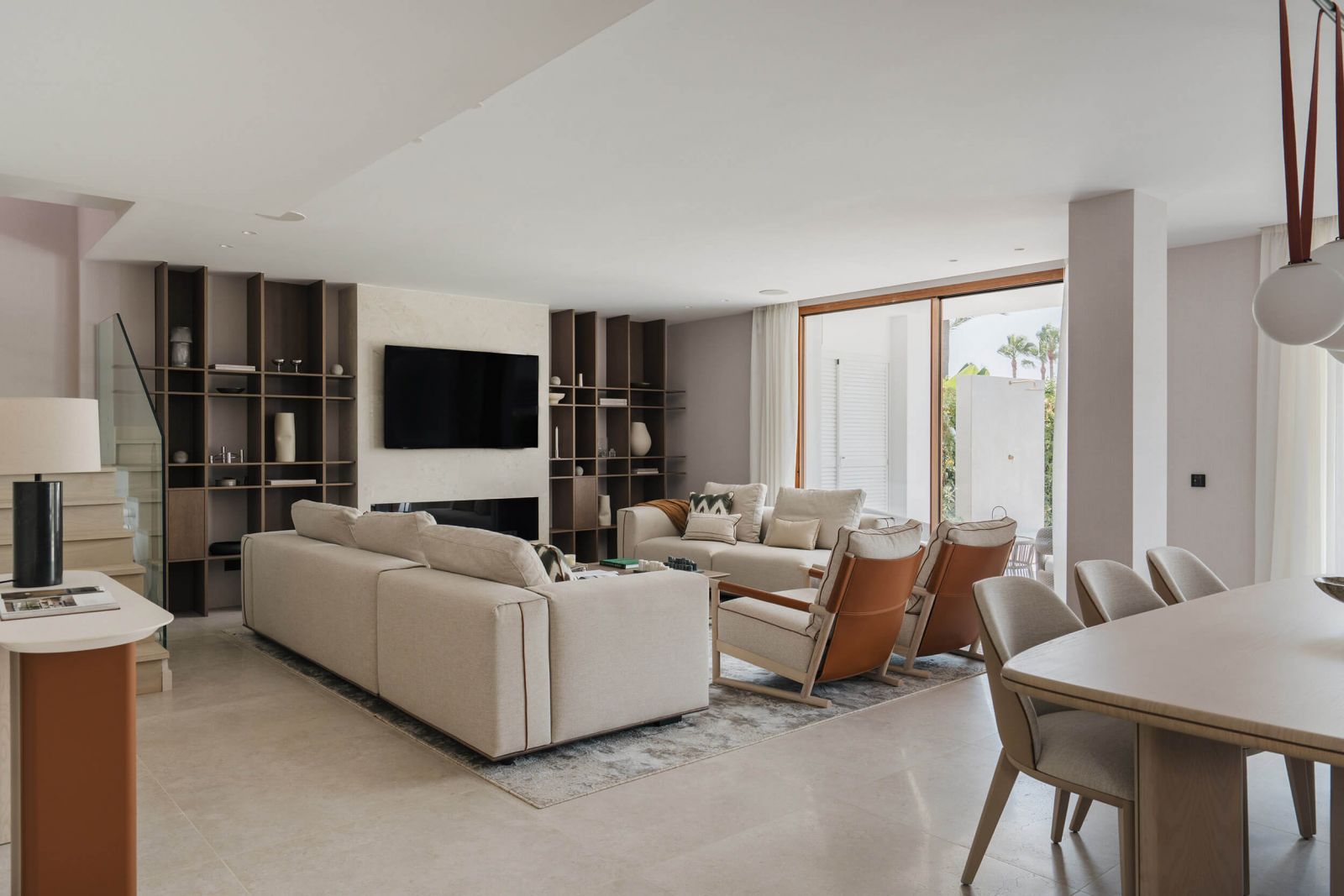 Zona de estar con sofá Capri y sillones Ischia de Alexandra, combinando tapizados claros, madera natural y respaldos de cuero para crear un espacio cálido y confortable creado por Xquisit Homes