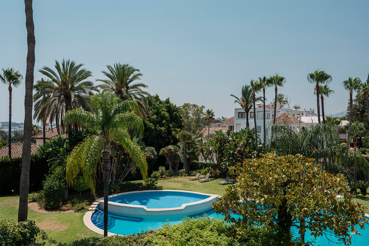 Vista exterior de una vivienda en Alcores del Golf, Marbella, con jardín privado, piscina y espacios exteriores conectados con el interior